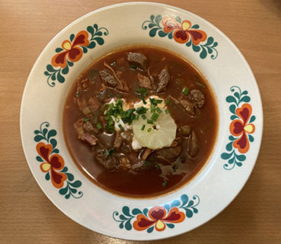 Soljanka, eine gehaltvolle Suppe, auf Fleischbasis, mit einem Klecks saurer Sahne und Toast versehen